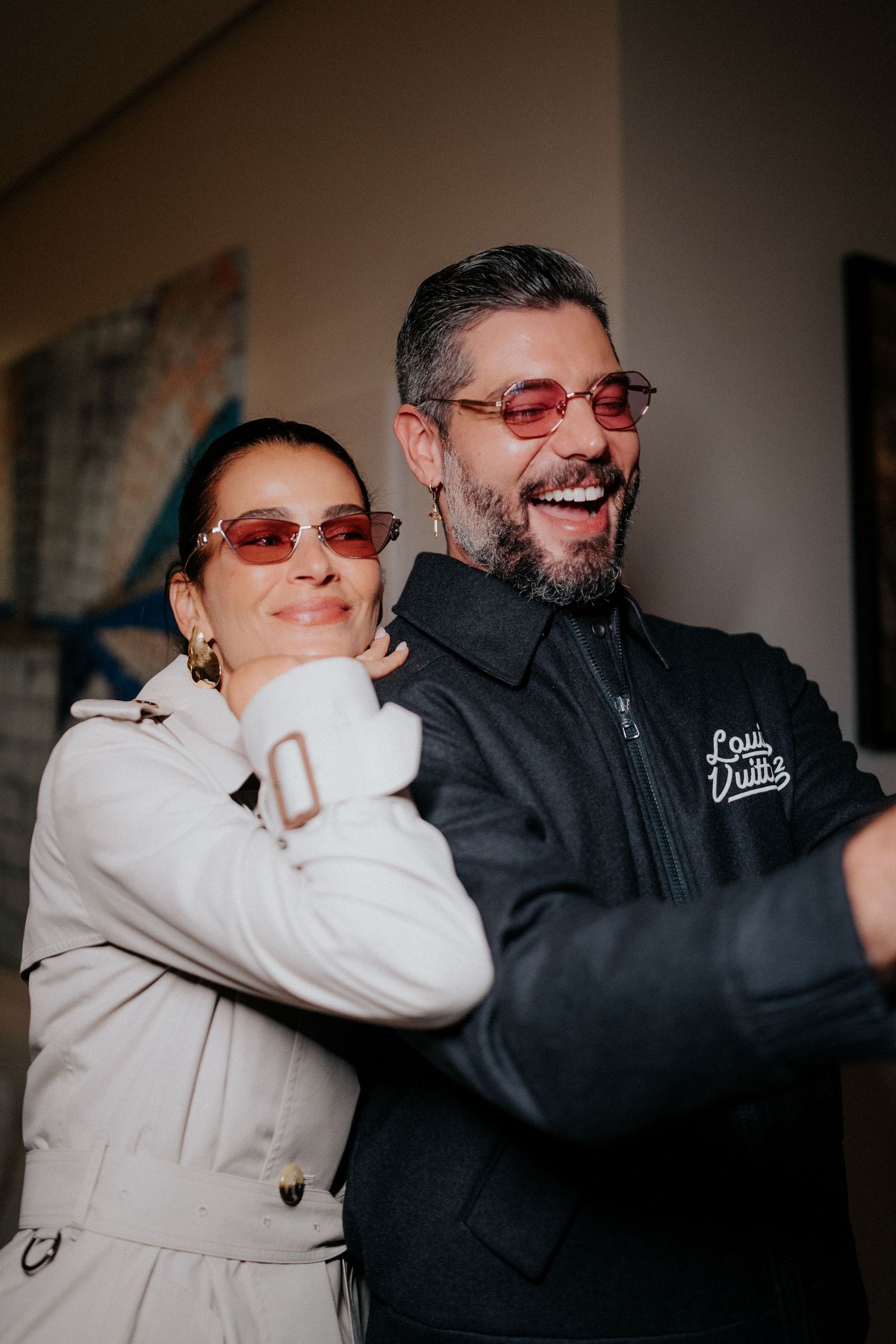 Two people sharing playful moment together while wearing sunglasses indoors.