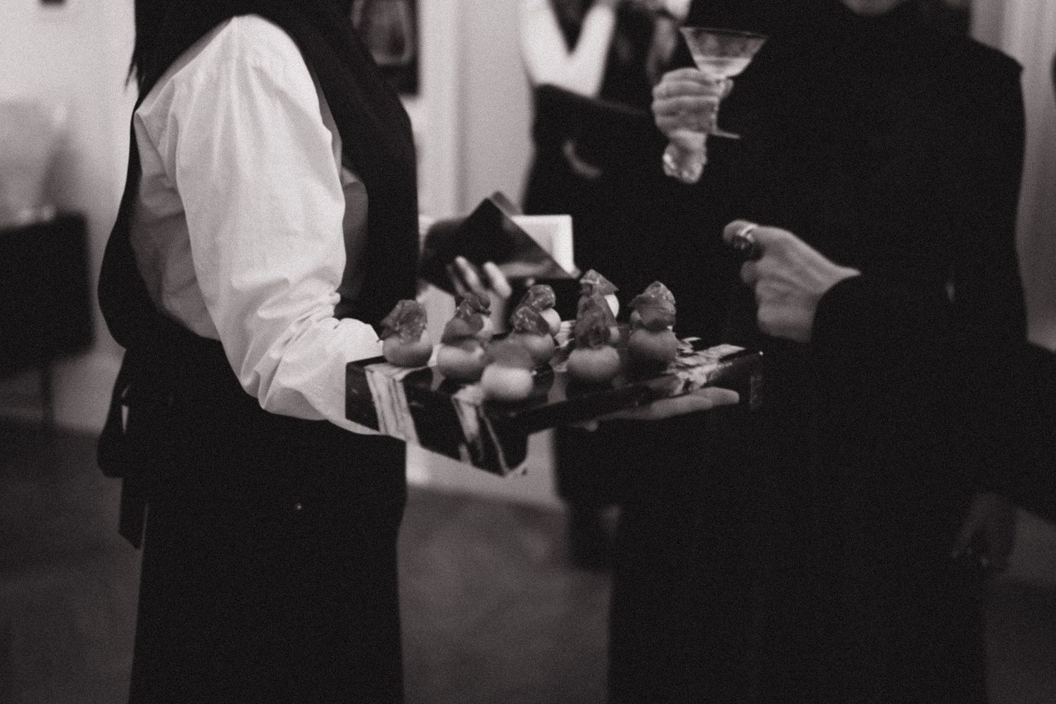 People mingling at evening social gathering in dimly lit room.