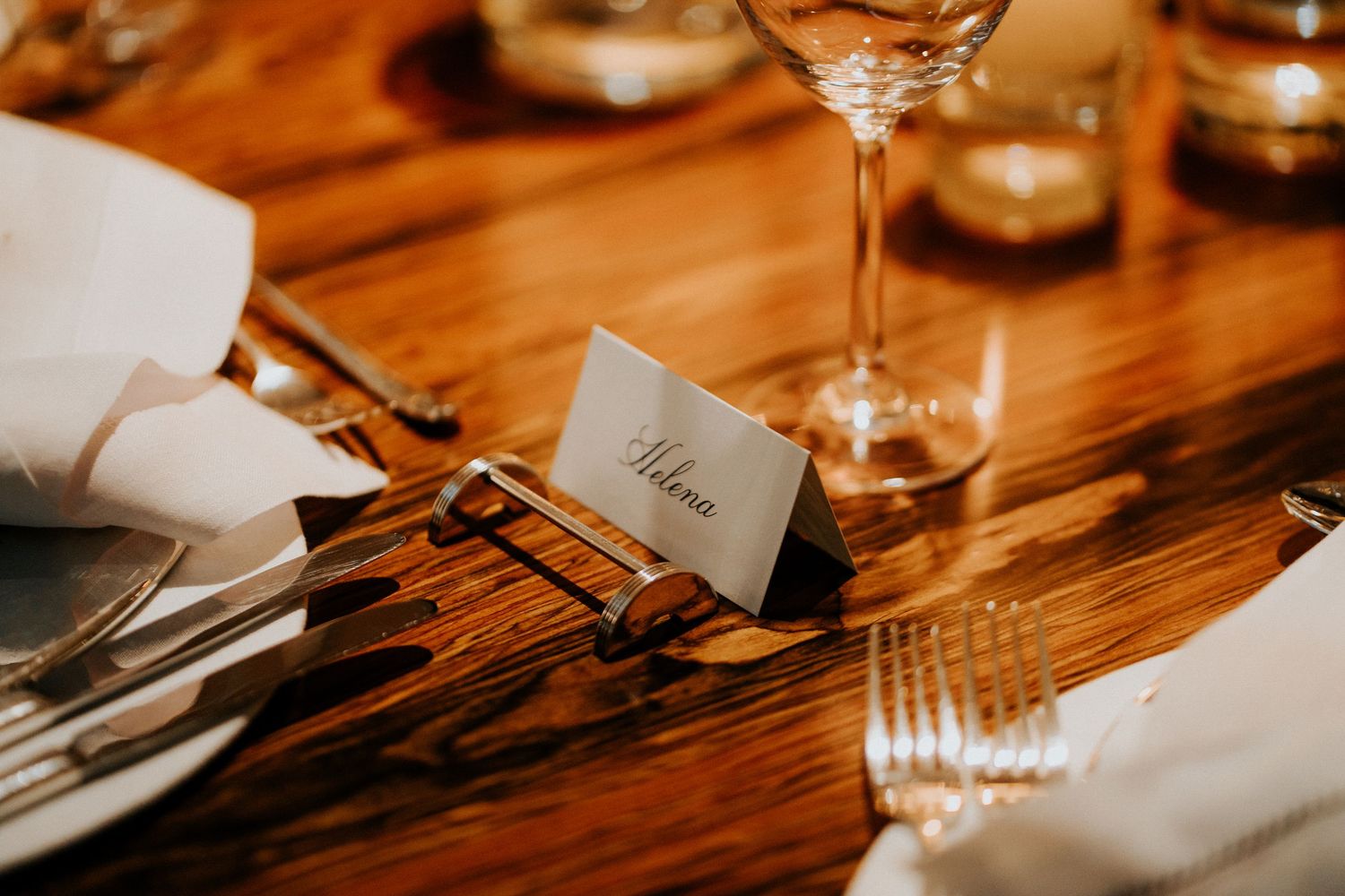 Close-up of elegant place settings on a rustic wooden table at a wedding reception.
