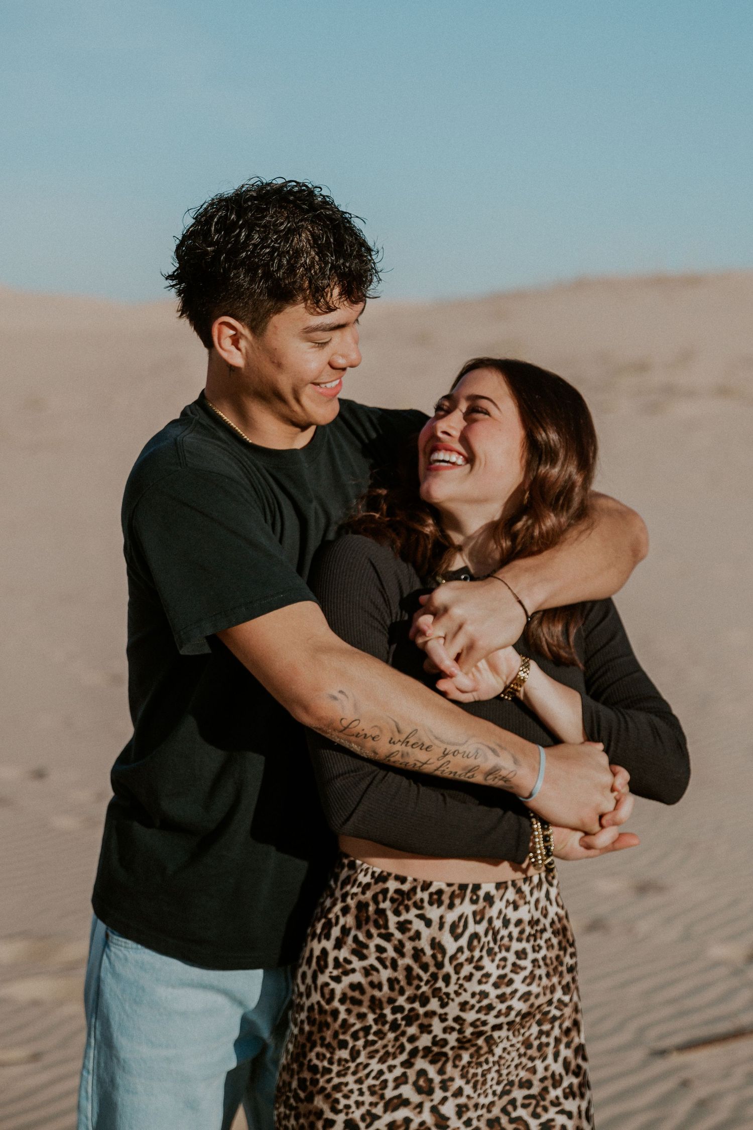 Young couple embrace each other in the sand dunes.