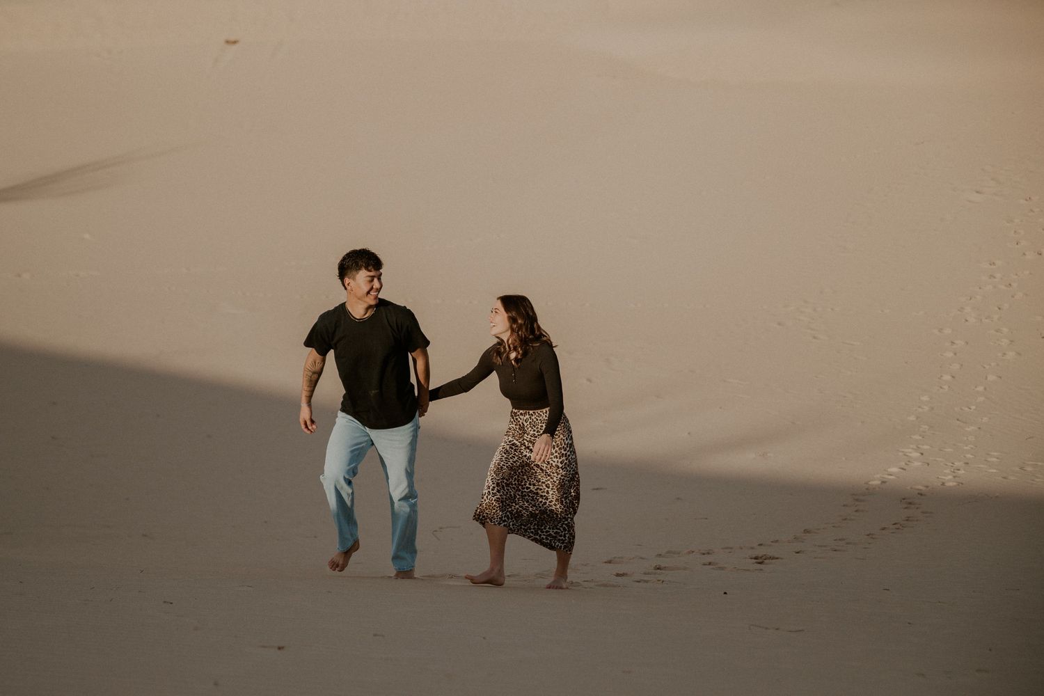 Young couple walk through the sand hills together.
