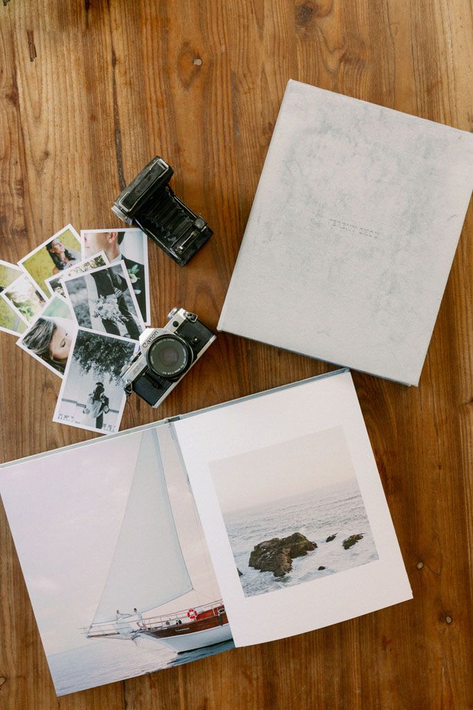 Black and white photographs and blank papers scattered across a rustic wooden table surface.