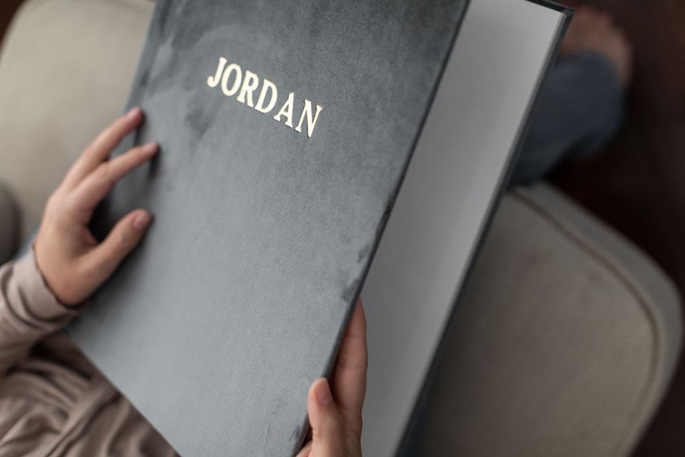 Pages of a stylish grey wedding photo album with names embossed on the cover in silver text.