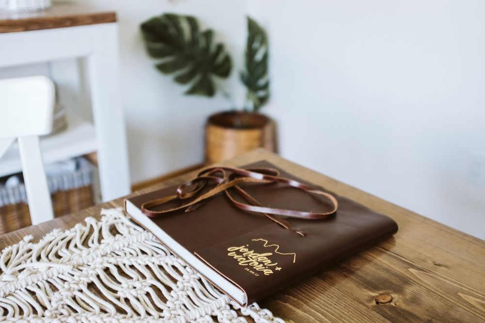 Modern wooden table display with tropical monstera leaf and white lace accent.
