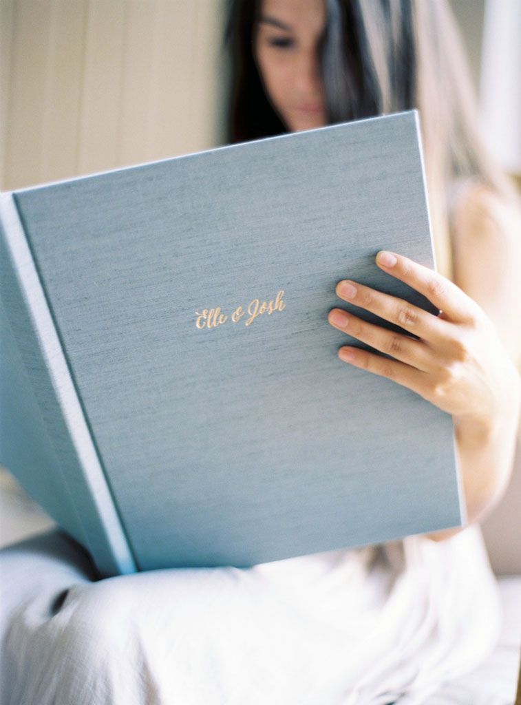 Multiple views of an elegant grey wedding album being held and displayed against a light background.