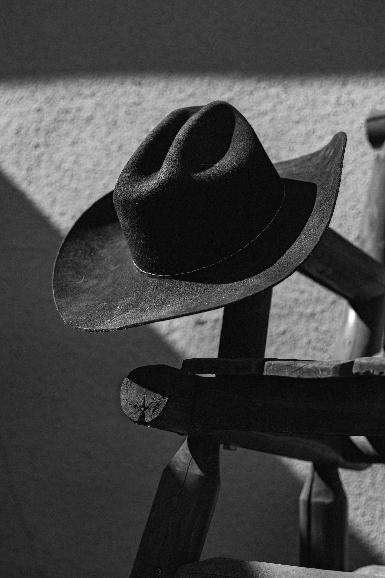 Series of black cowboy hats creating shadows on a white textured wall.