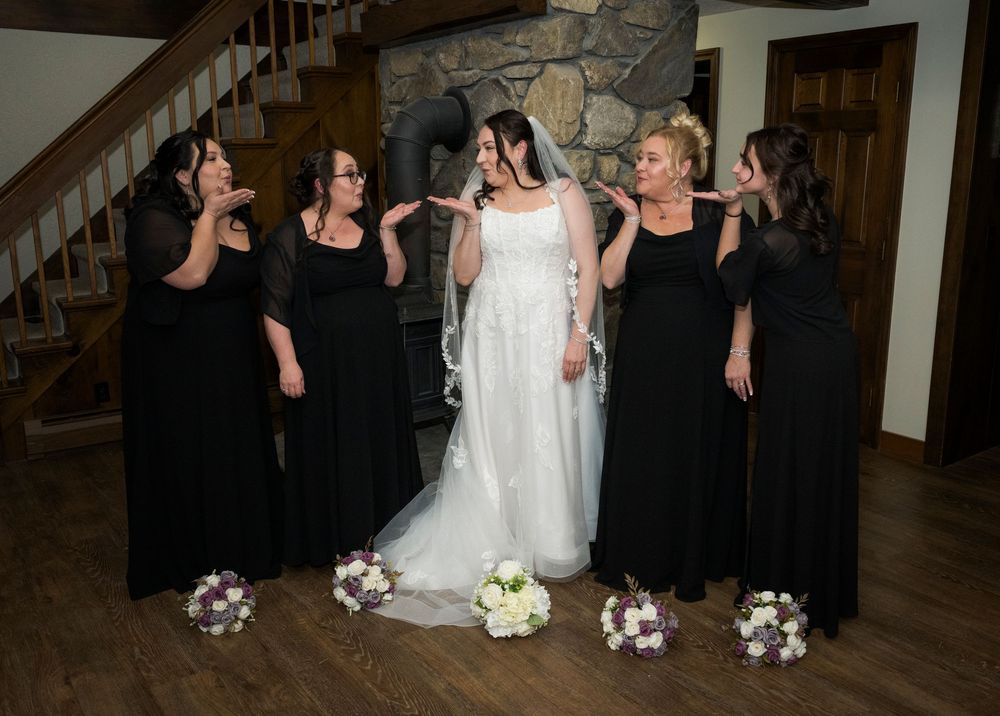 Wedding party members dance and celebrate together in a candid line formation at an indoor reception venue.