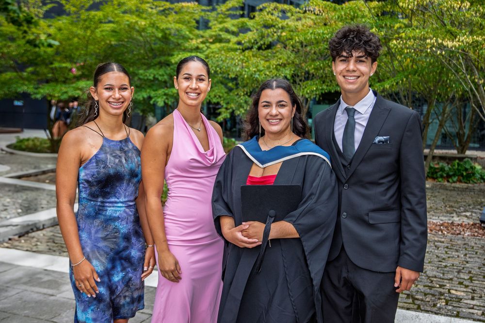 Family and friends gather for graduation photos in casual and formal attire outdoors.