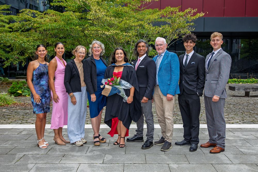 Multi-generational family group photo taken outdoors during graduation festivities.