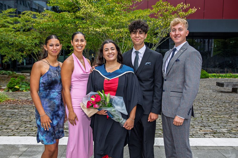 Graduation celebration group photo with family members in formal and casual wear.