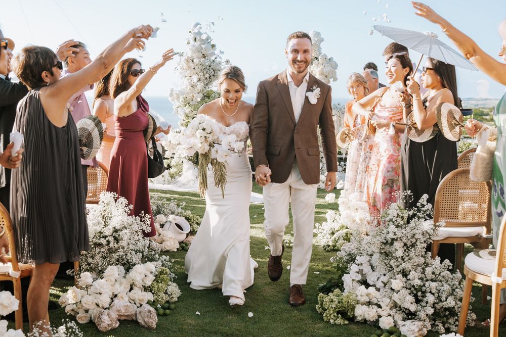 Dancing and celebrating at an outdoor wedding reception with white floral decorations under a sunny sky.