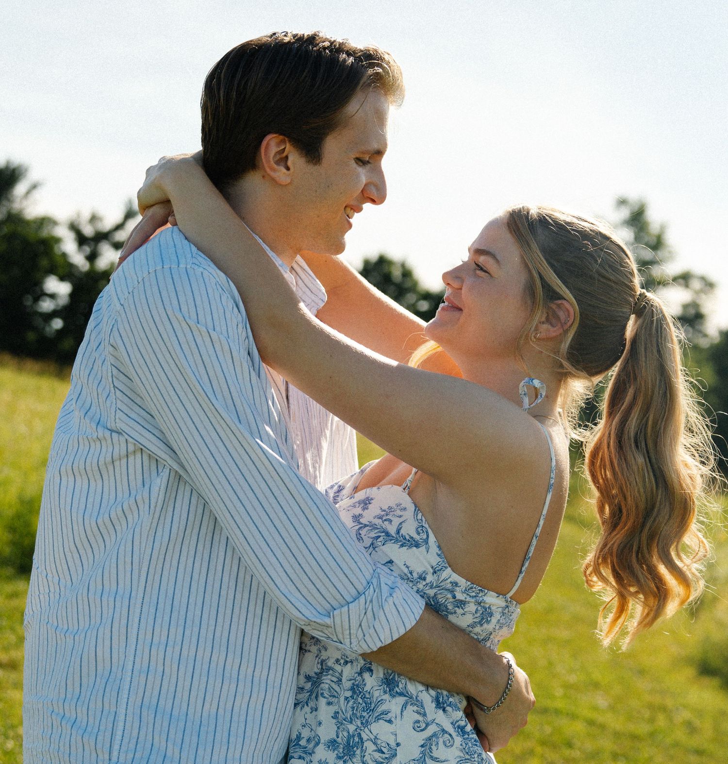 Couple sharing a joyful embrace among yellow wildflowers in a natural outdoor setting.