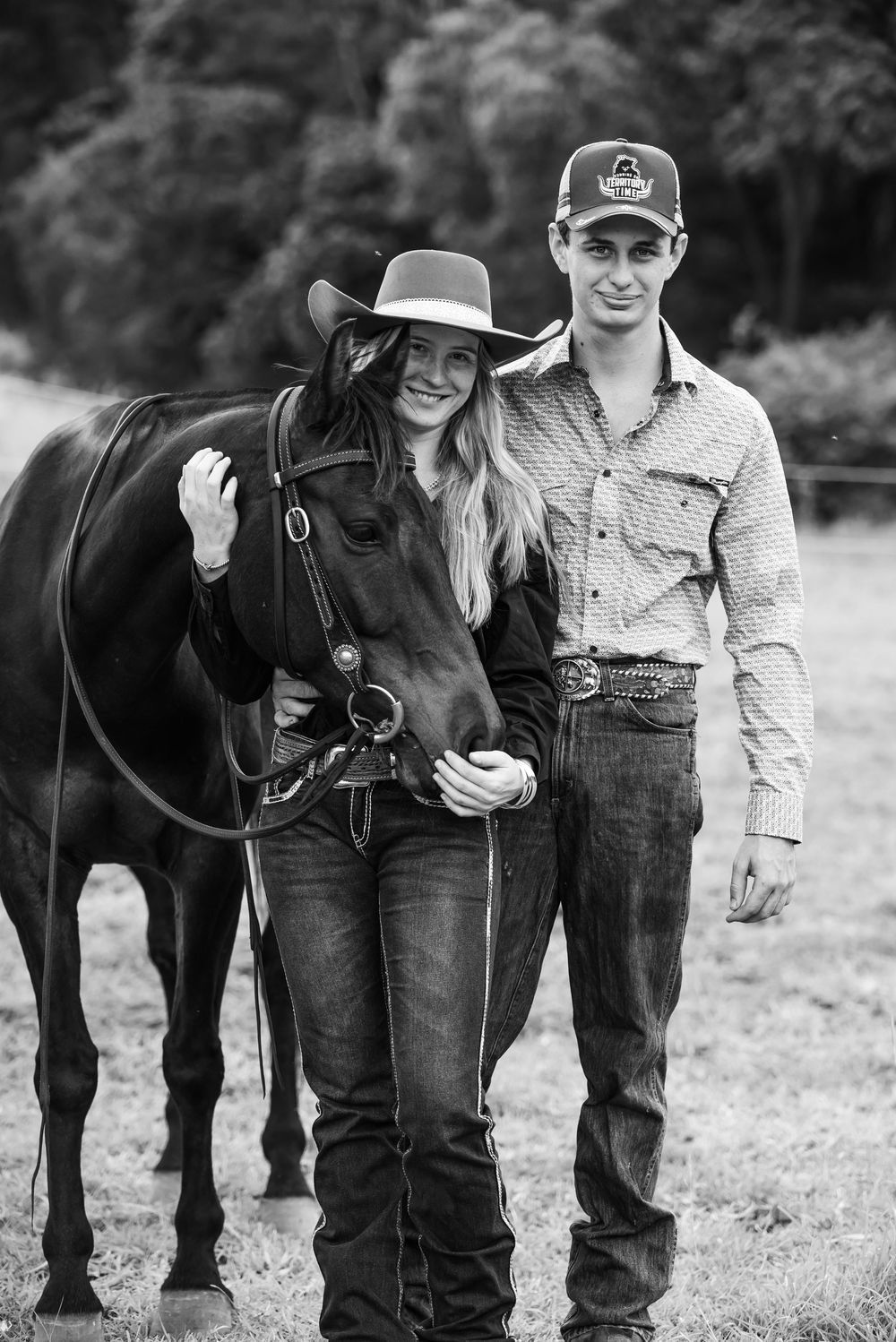 Black and white engagement photos show a couple posing outdoors with their horse in a romantic countryside setting.