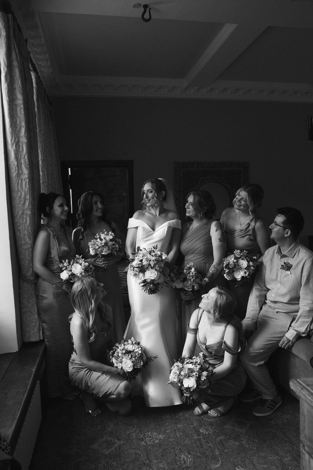 Black and white photo of wedding party members sitting together in a casual group pose.