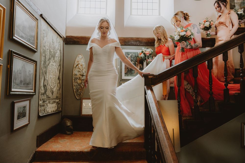 Wedding party members walking through an elegant hallway with artwork and wooden details.