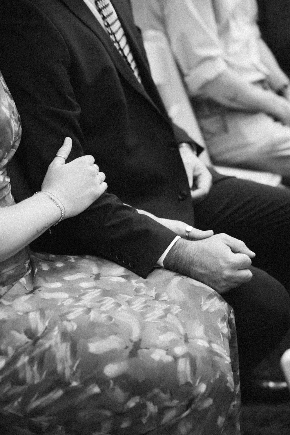 Black and white detail shots of formal attire and hands during a wedding ceremony.