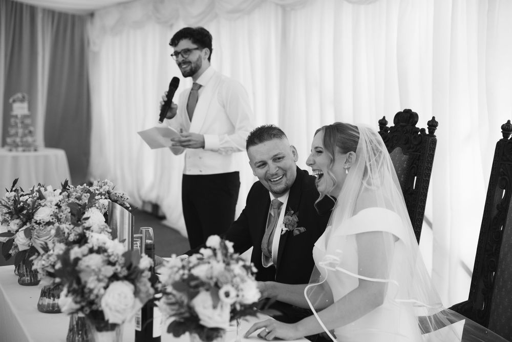 Wedding reception scene with white draping and floral centerpieces.