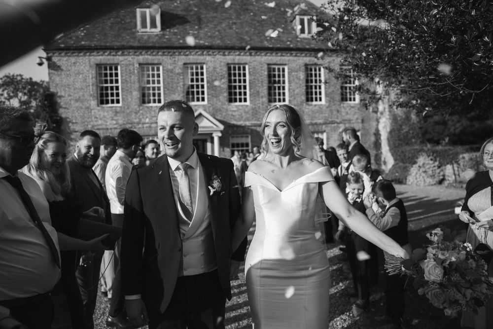 Black and white photos of wedding guests celebrating outside a historic brick building.