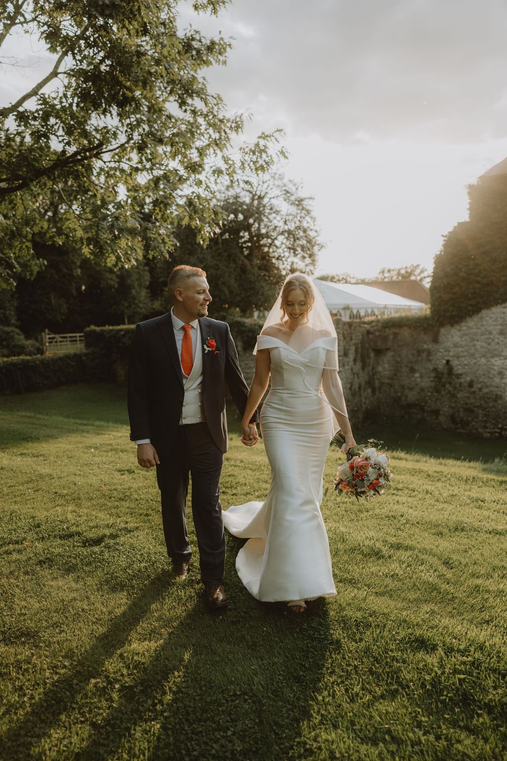 Sunset wedding photos on a grassy hill with golden hour lighting and trees in background.