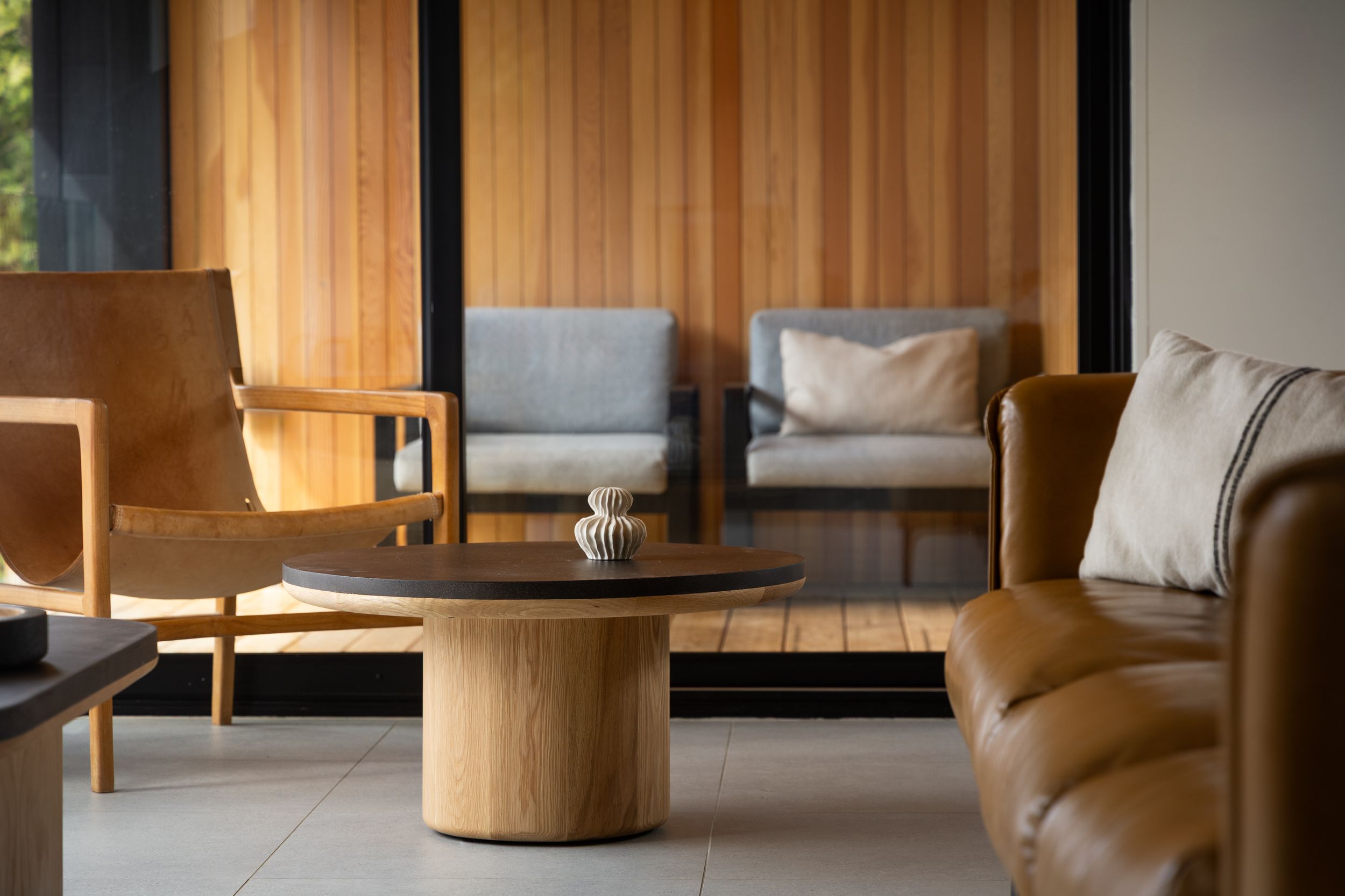 Modern living room interior with wooden furniture and glass panels featuring minimalist contemporary design elements.