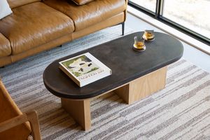 A modern living room interior with wooden coffee tables and leather sofa on a gray striped area rug.