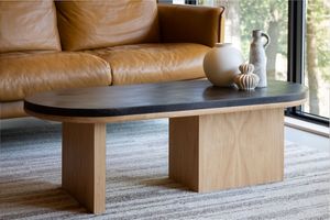 Modern wood coffee table with plank-style base and sleek rectangular top sitting on neutral carpet.