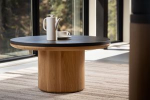 Contemporary wooden side tables with rounded black tops arranged in a row against a window in minimalist setting.