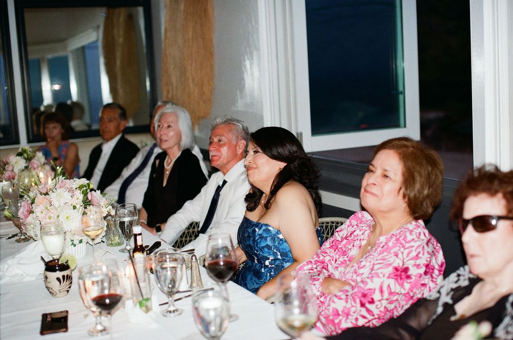 Emotional 35mm film photo of parents watching toasts at a Malibu coastal wedding.
