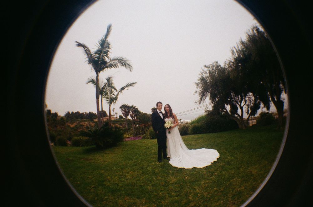 Malibu film photographer uses a fisheye lens for a creative portrait of the bride and groom on PCH.