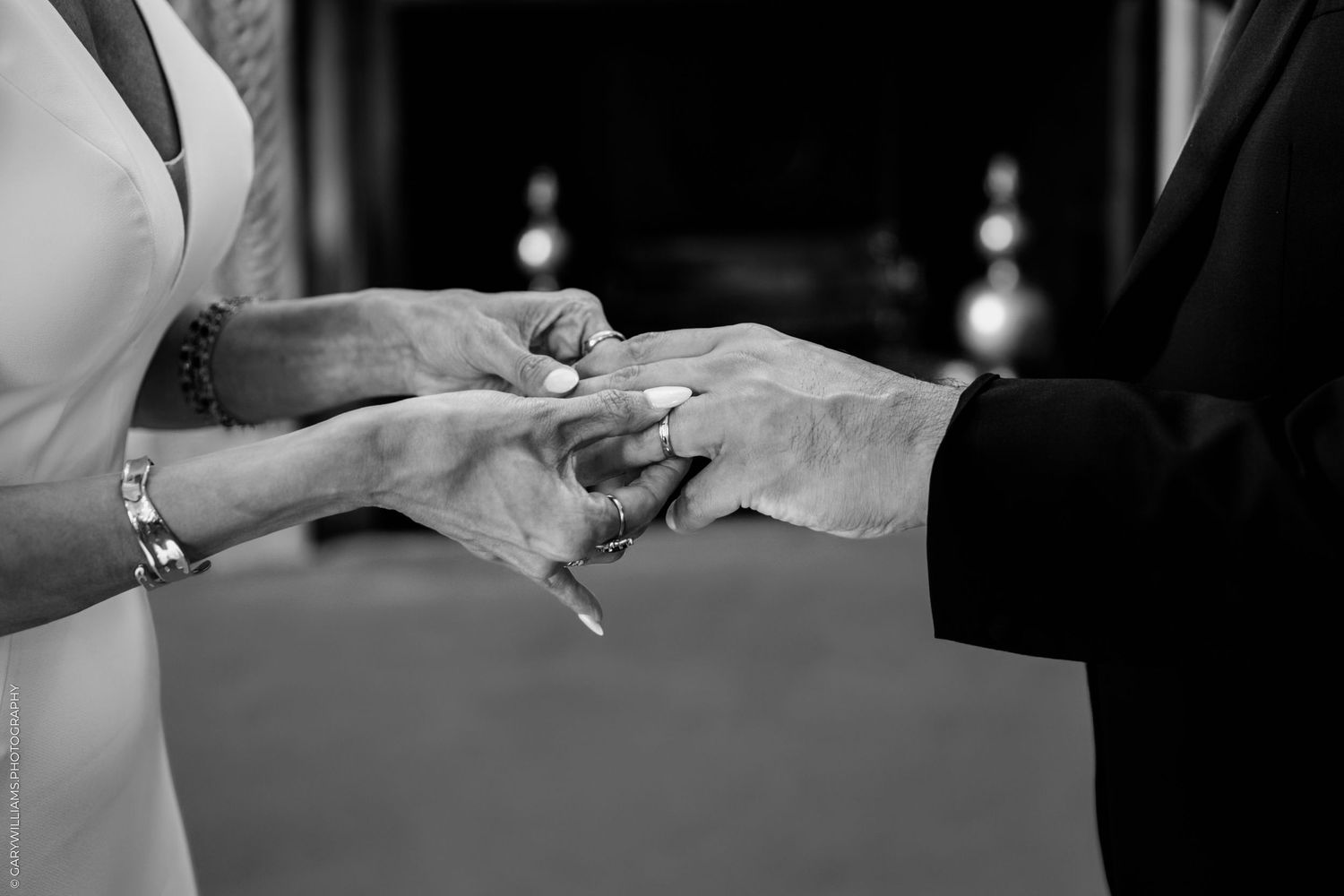 A black and white close-up photograph capturing the exchange of rings during a wedding ceremony.