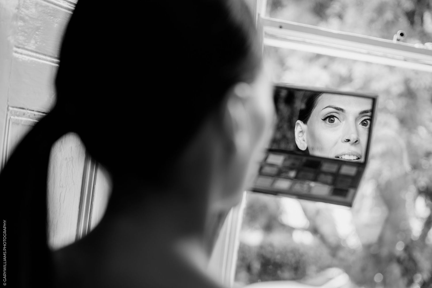 Black and white artistic photograph of a person looking in a mirror showing dramatic reflection.