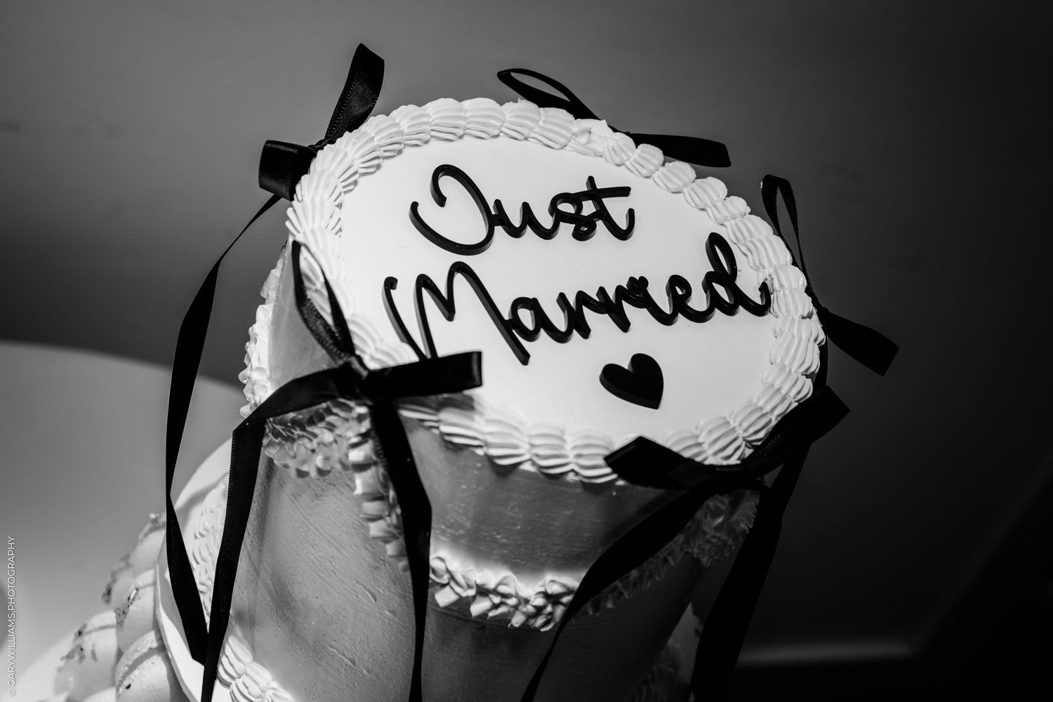A black and white image of a 'Just Married' sign with decorative lace and ribbon details.