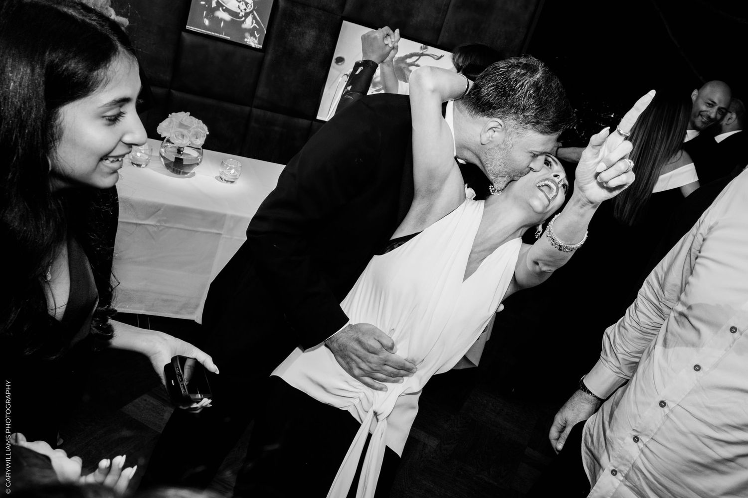 Black and white photograph showing people dancing energetically at a lively party or celebration.