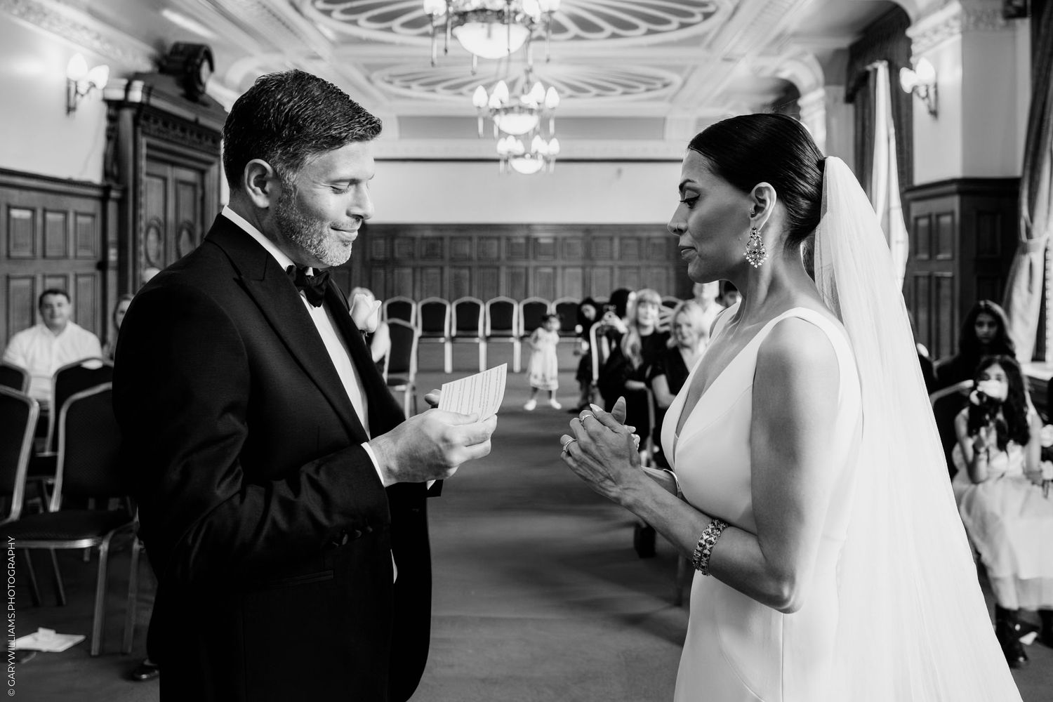 Two people share a moment while holding champagne glasses during a wedding celebration in an elegant room.