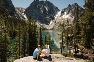 romantic picnic overlooking a turquoise alpine lake surrounded by snow-capped mountains and evergreen trees.    Colchuck Lake proposal