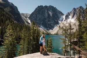 A majestic mountain lake surrounded by evergreen forest and snow-capped peaks in a scenic wilderness landscape.