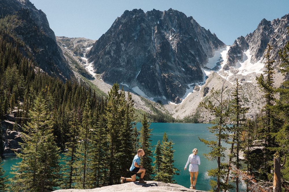 A turquoise alpine lake surrounded by snow-capped mountain peaks and evergreen forest in the Canadian Rockies.