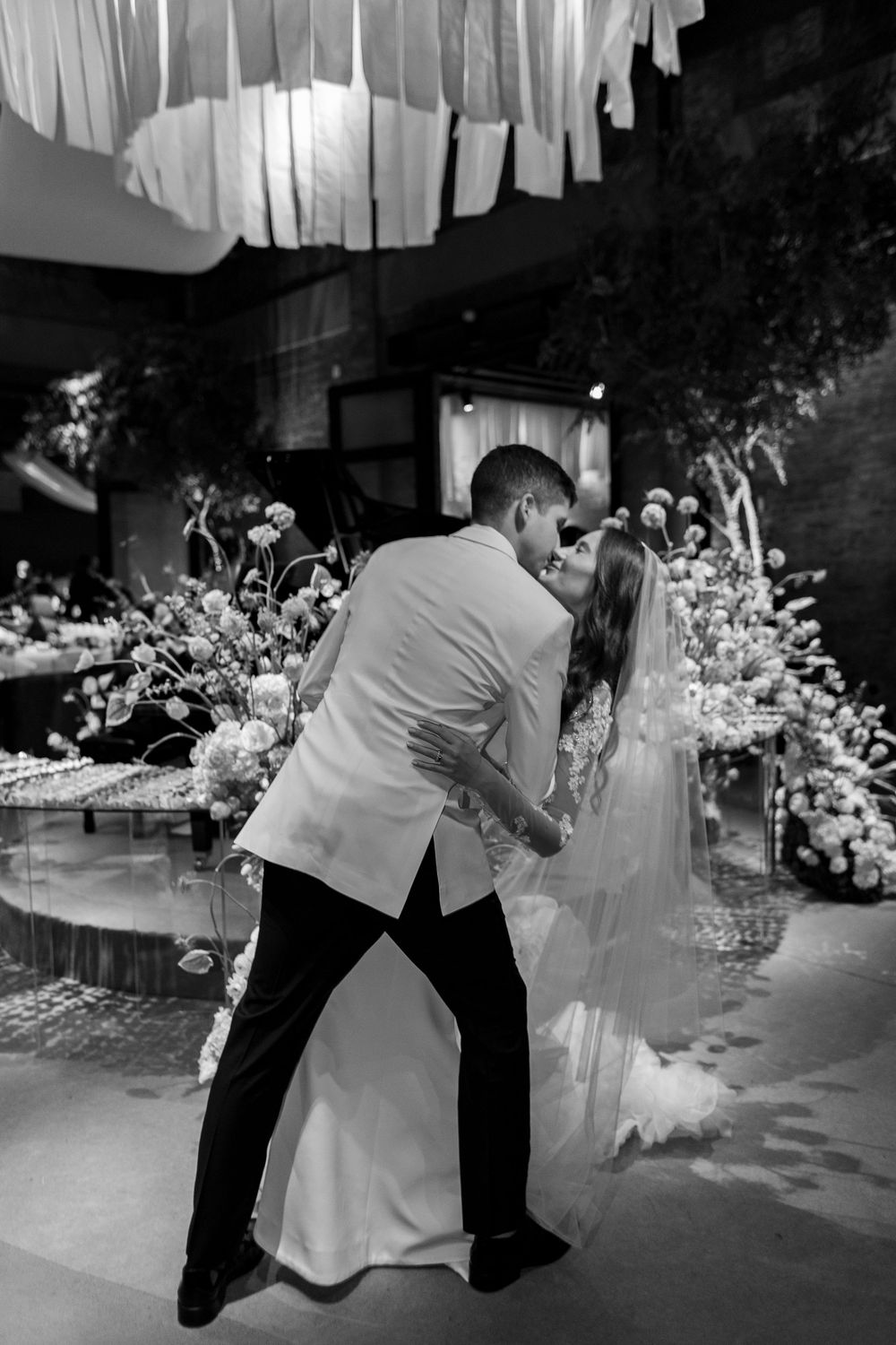An intimate dance sequence showing dancers dipping in formal wedding attire with floral arrangements in the background.
