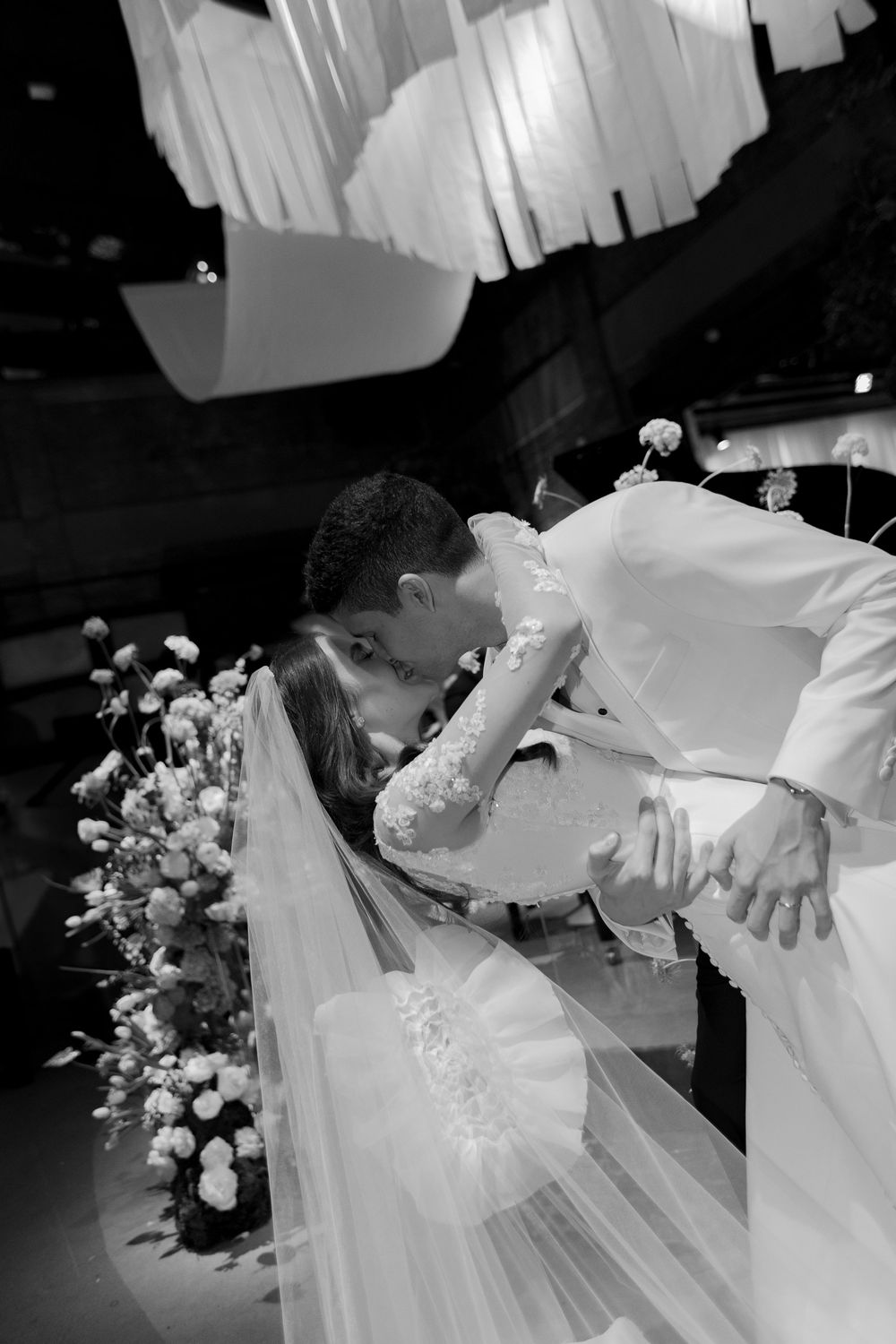 Black and white wedding celebration photos showing details of a white dress, veil, and floral bouquet across multiple frames.