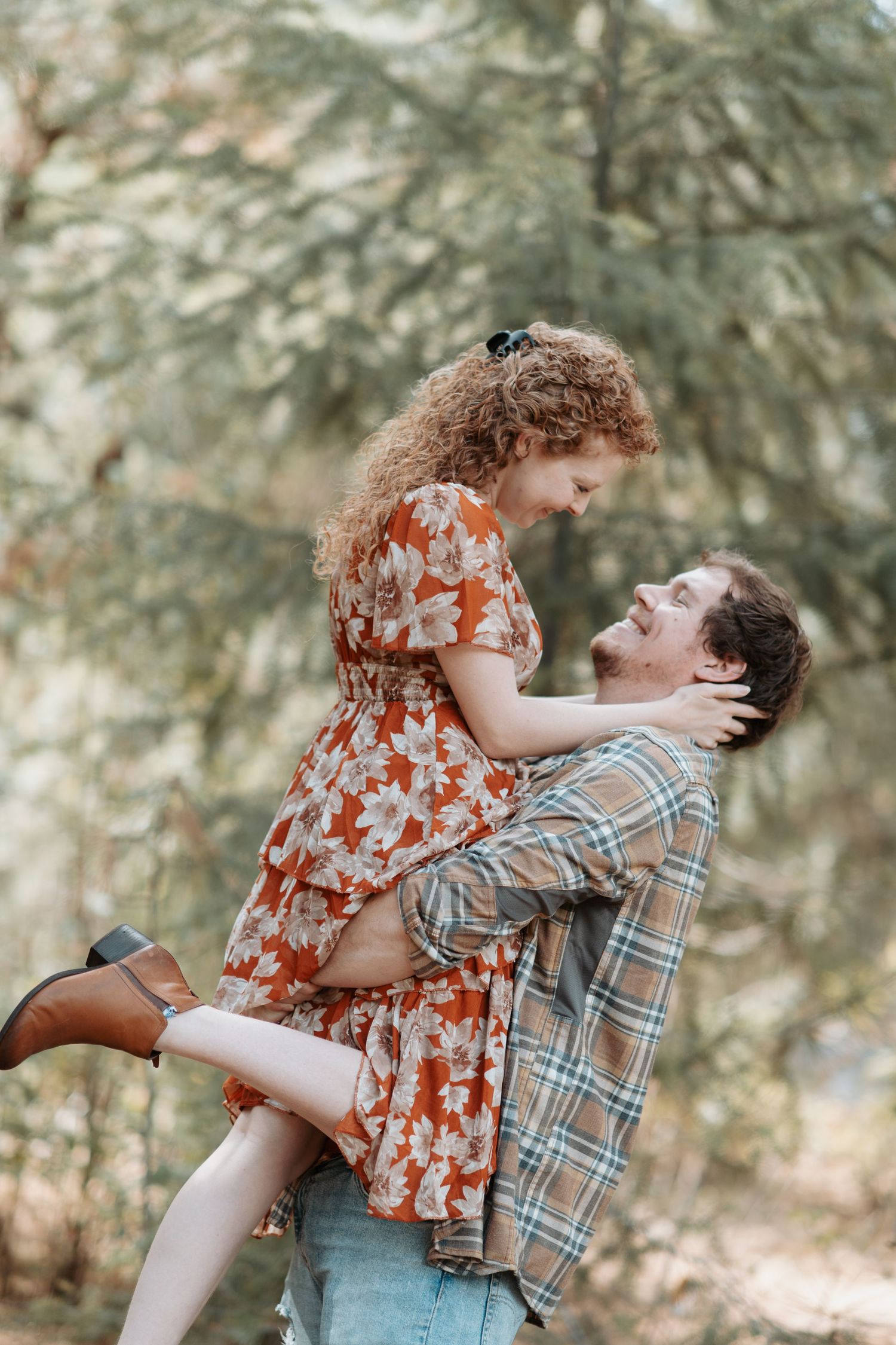 Young man lifting his fiance up and looking at each other in the eyes during their engagement session in Post Falls, Idaho.