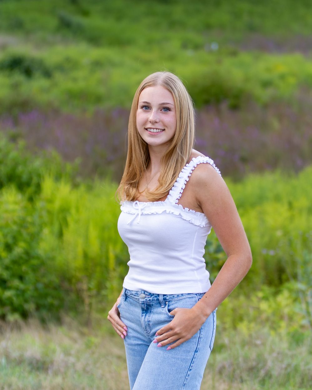 A high school senior poses for her yearbook portraits in a wildflower field at Wolbach Farm in Sudbury, MA with Lisa West Photography.