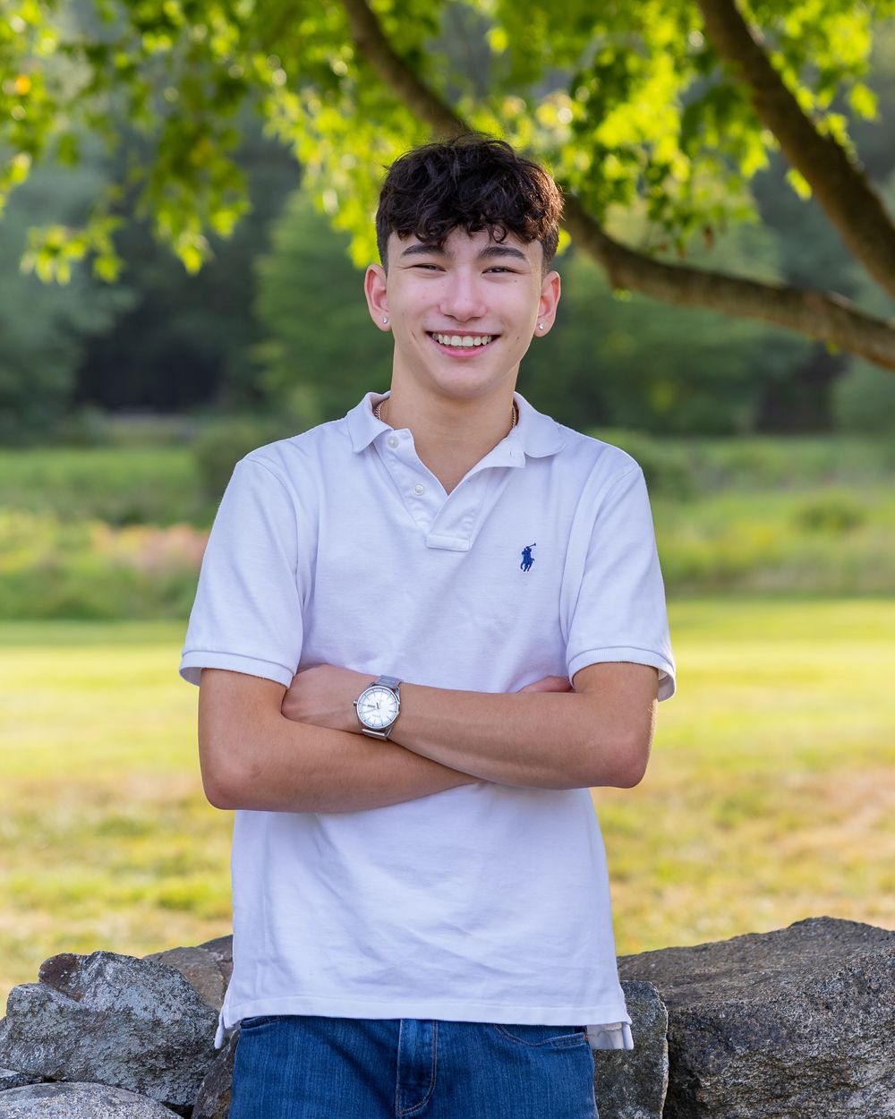 A high school senior poses for his yearbook portraits along a stone wall at the Codman Estate in Lincoln, MA with Lisa West Photography.
