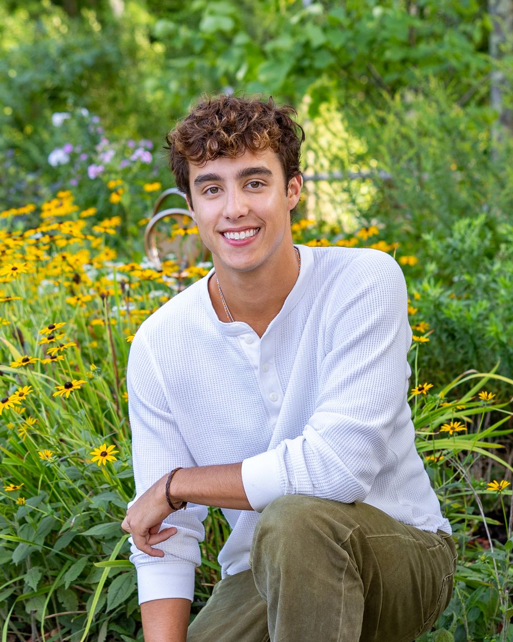 A high school senior poses for his yearbook portraits with wildflowers at Heritage Park in Sudbury, MA with Lisa West Photography.