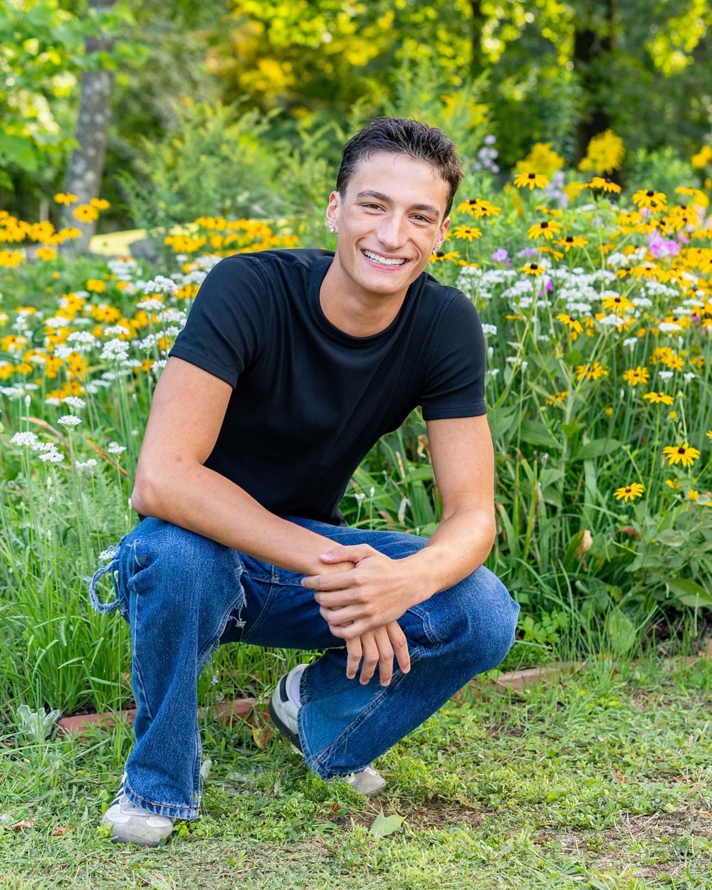 A high school senior poses for his yearbook portraits with wildflowers at Heritage Park in Sudbury, MA with Lisa West Photography.