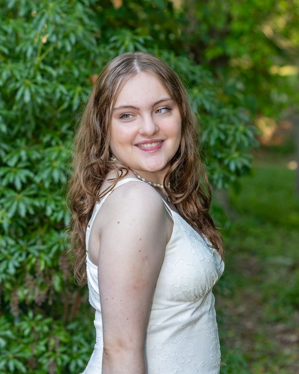A high school senior poses for her yearbook portraits in a botanical garden in Falmouth, MA on Cape Cod with Lisa West Photography.