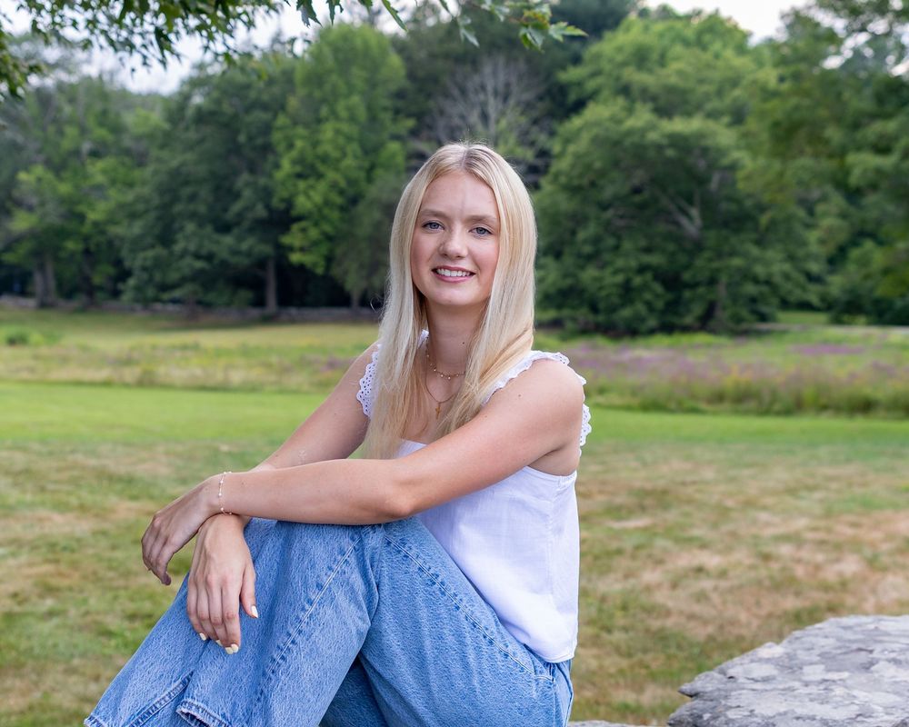 A high school senior poses for her yearbook portraits along a stone wall at the Codman Estate in Lincoln, MA with Lisa West Photography.