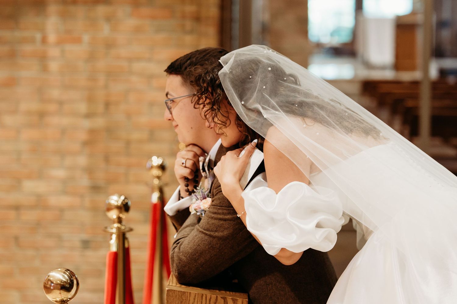 A bride hugs her groom from behind  in the Adoration Chapel doing their "first touch" before their Catholic wedding Mass.
