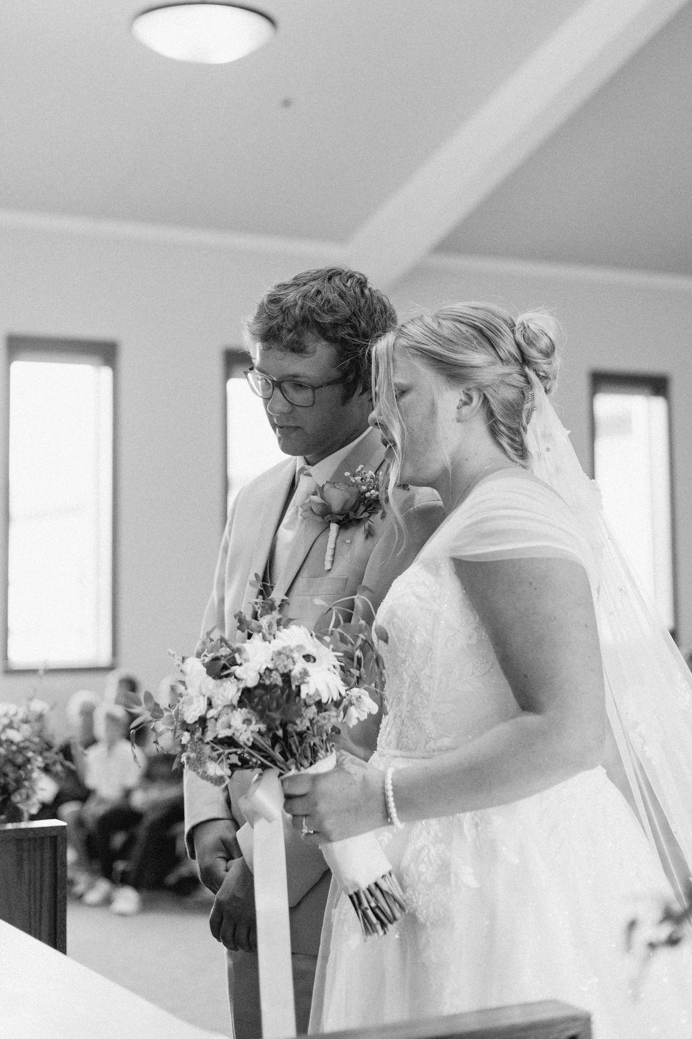 A couple shares a tender moment during their wedding ceremony in a light-filled chapel.