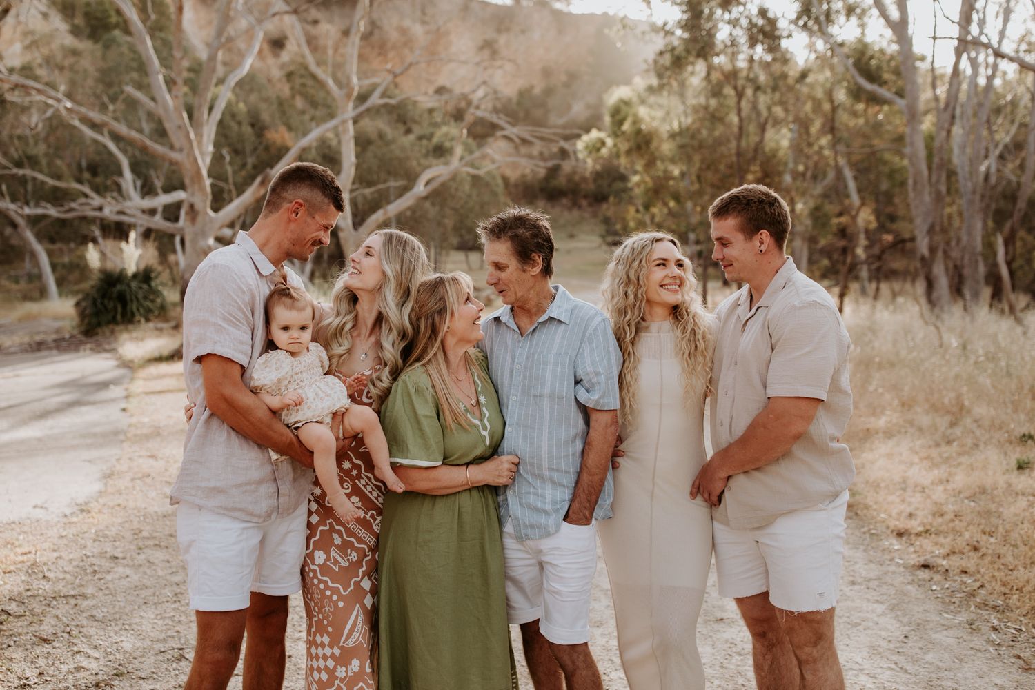 An extended family photography session in a field and the family cuddles and laughs with their dog with Lauren Lunn Photography in Adelaide.