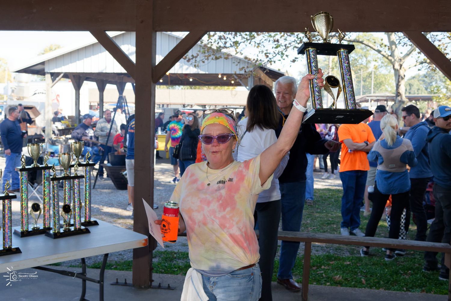 Community gathering awards presentation under pavilion during outdoor event.